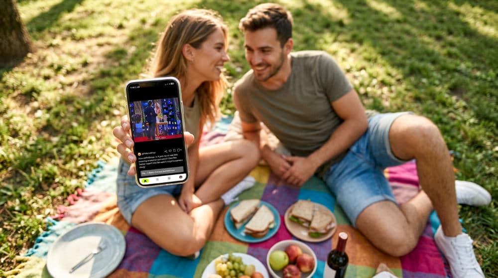 A couple seated outdoors with knees bent and arms angled to create artistic triangles in the photo layout.